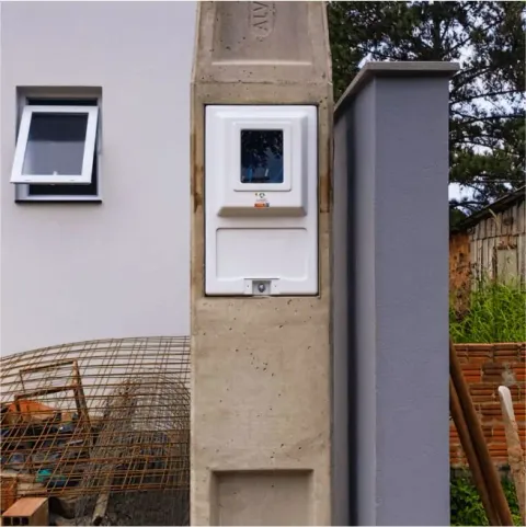 Caixa de medição instalada em poste de concreto em frente a um imóvel