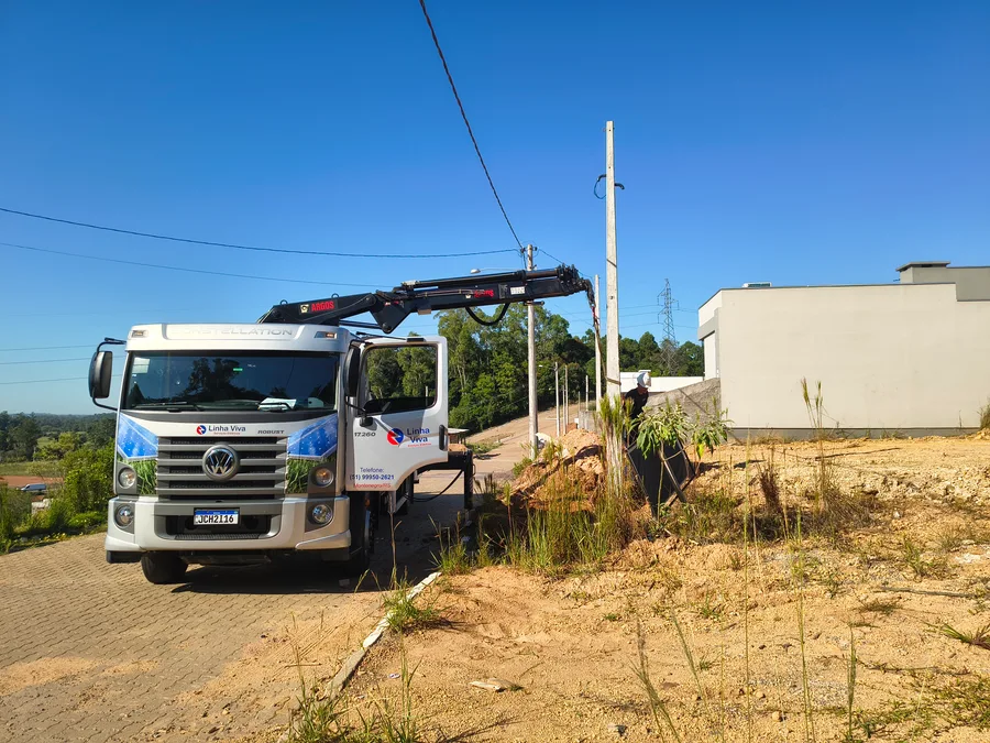Caminhão do Grupo Linha Viva auxiliando na instalação de poste junto a uma residência