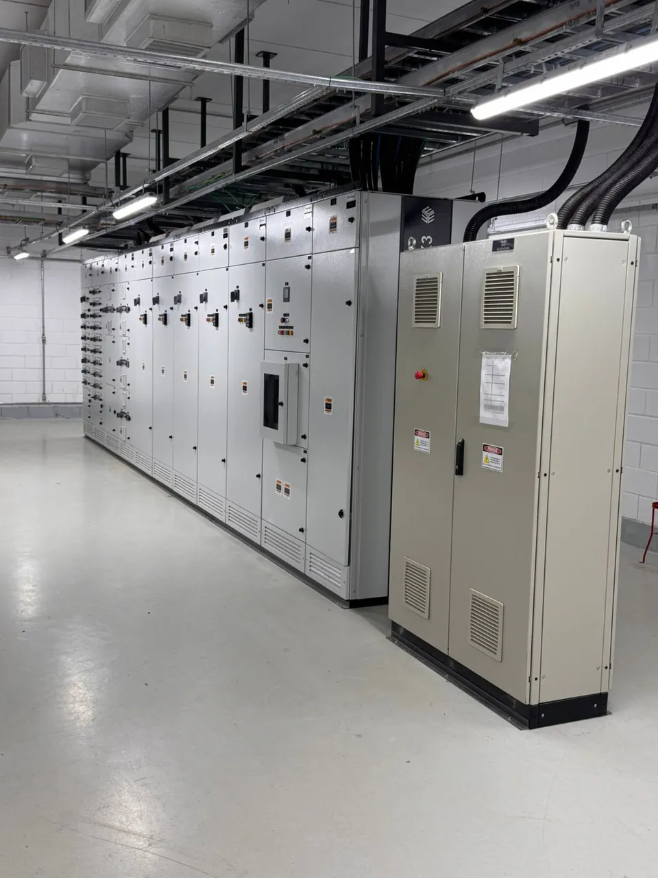 Painéis elétricos em sala técnica com infraestrutura de cabos e eletrocalhas
