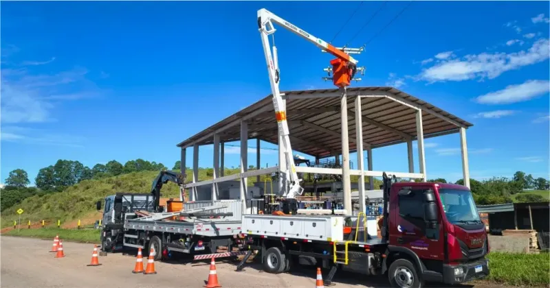 Caminhão com cesto aéreo em frente a uma estrutura industrial