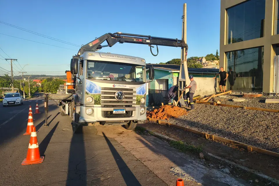 Equipe e caminhão guindaste na instalação de poste para entrada de energia