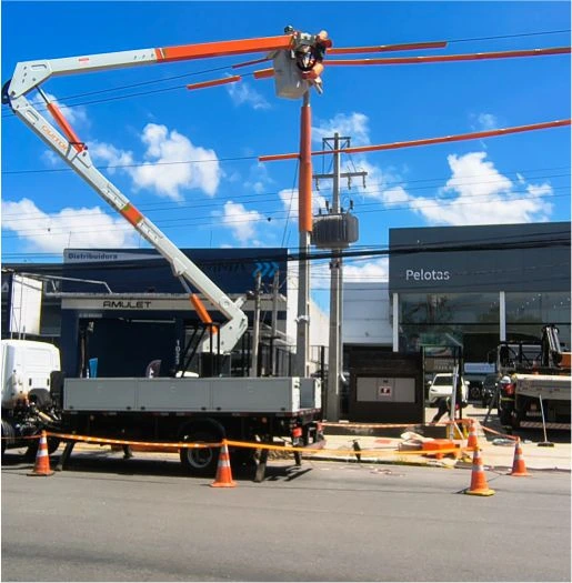Caminhão do Grupo Linha Viva com cesto aéreo realizando serviço em rede elétrica energizada em área comercial na cidade de Pelotas, RS